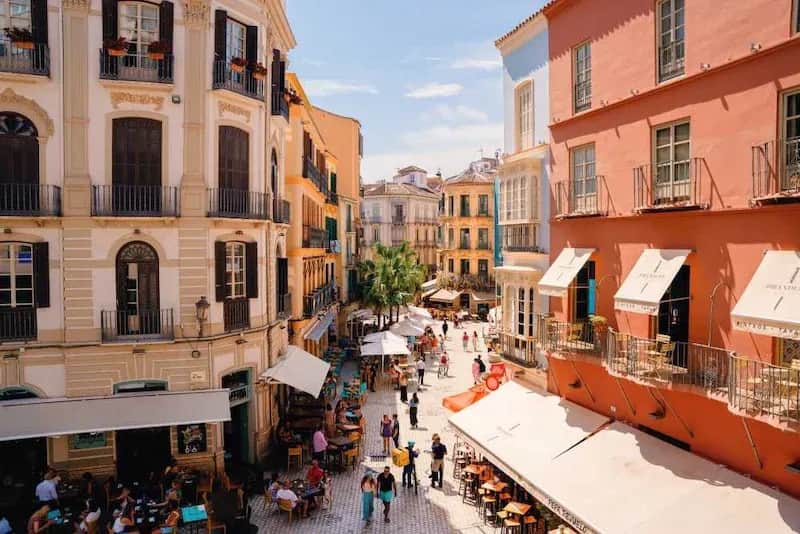 View of Málaga’s historic city center with colorful buildings, outdoor cafés, and people walking through the streets.